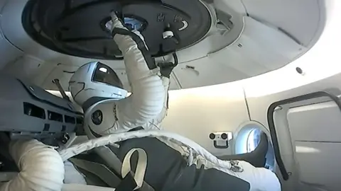 SpaceX Polaris Dawn crew member prepares to open hatch before spacewalk